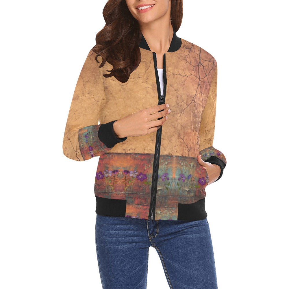 Woman wearing Rusty Life Bomber Jacket with abstract rust and floral artwork, black ribbed collar, cuffs, and hem, paired with blue jeans.