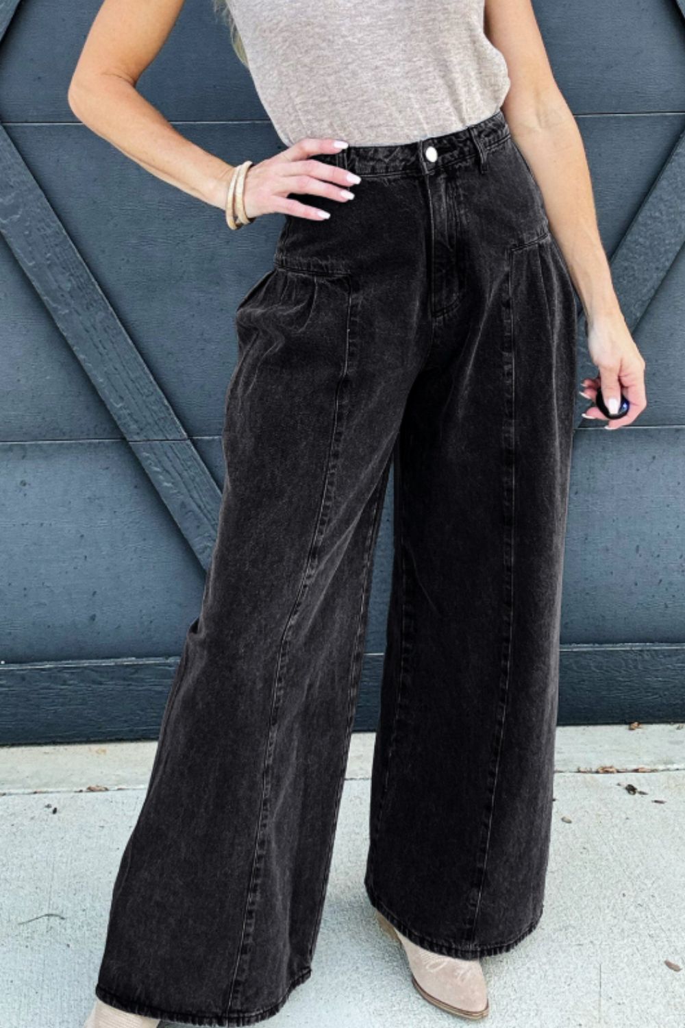 Black high rise wide leg jeans with pockets on model against gray background