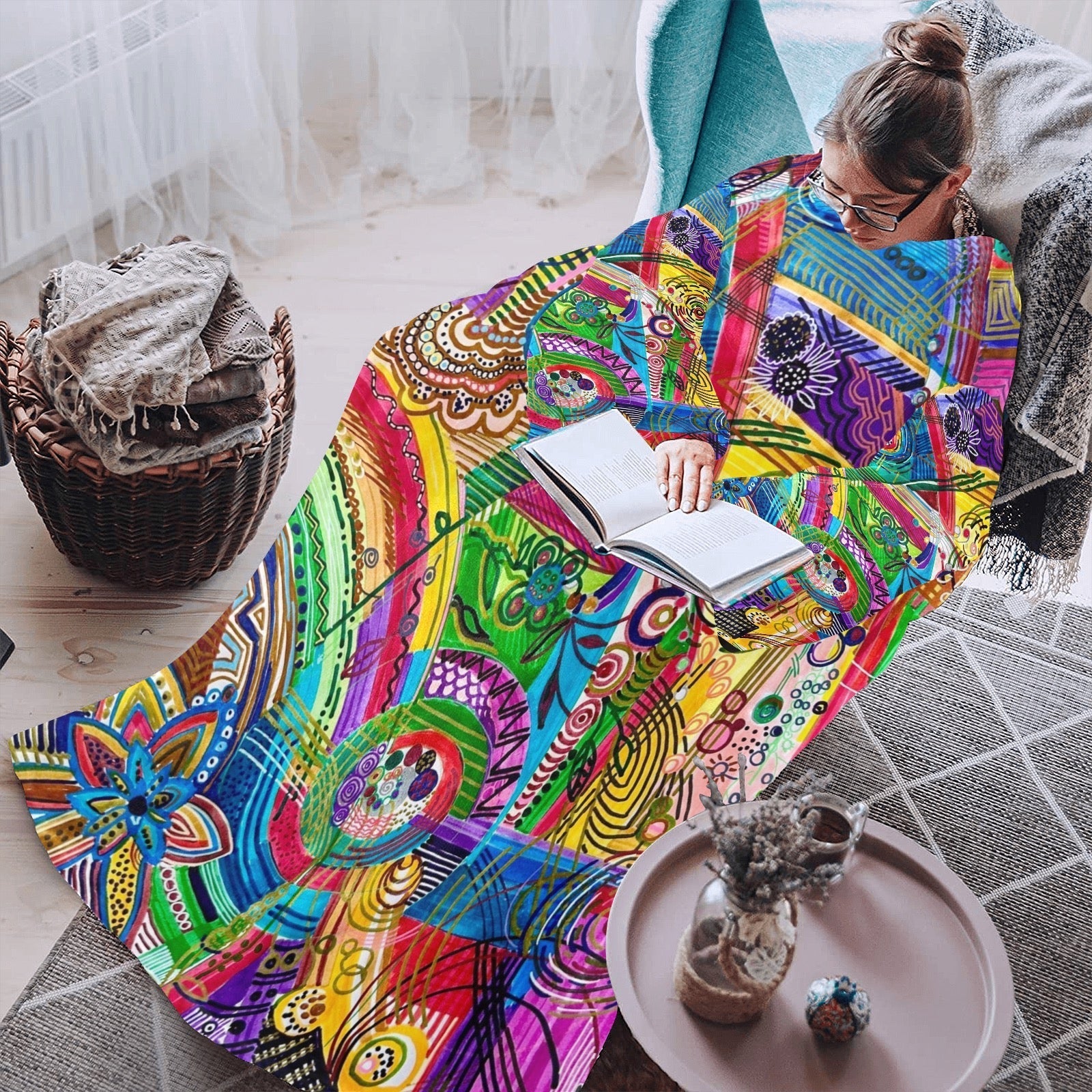 Woman wearing colorful Away with Winter Blues blanket robe with sleeves while reading indoors