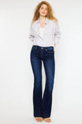 Woman wearing Kancan mid rise slim flare dark stonewash jeans with white shirt and sandals.