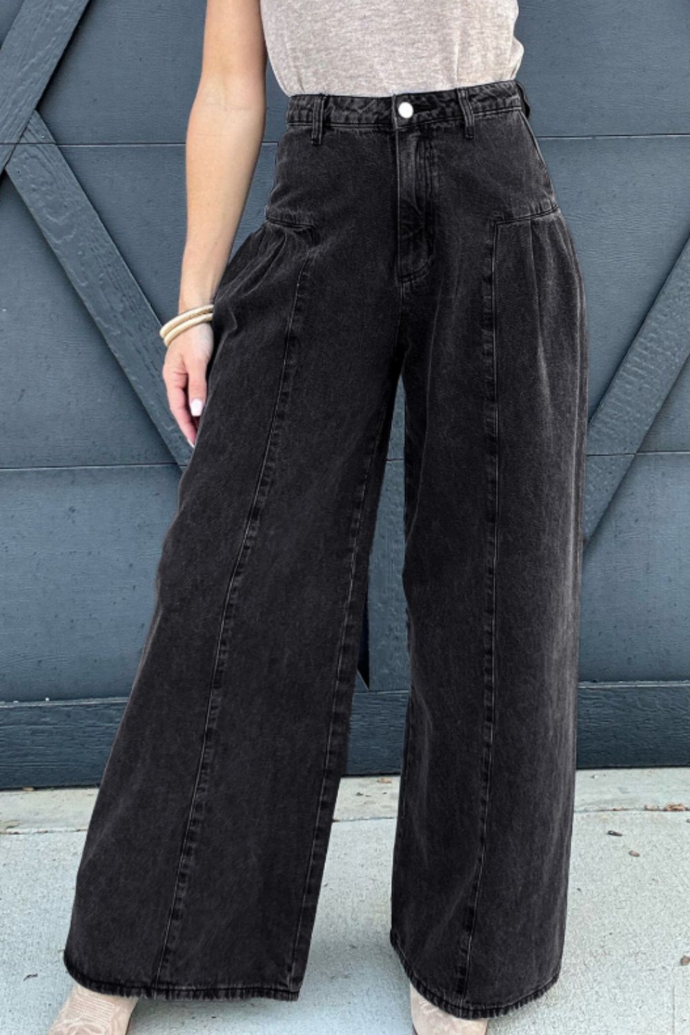 Black high rise wide leg jeans with pockets on model against gray background