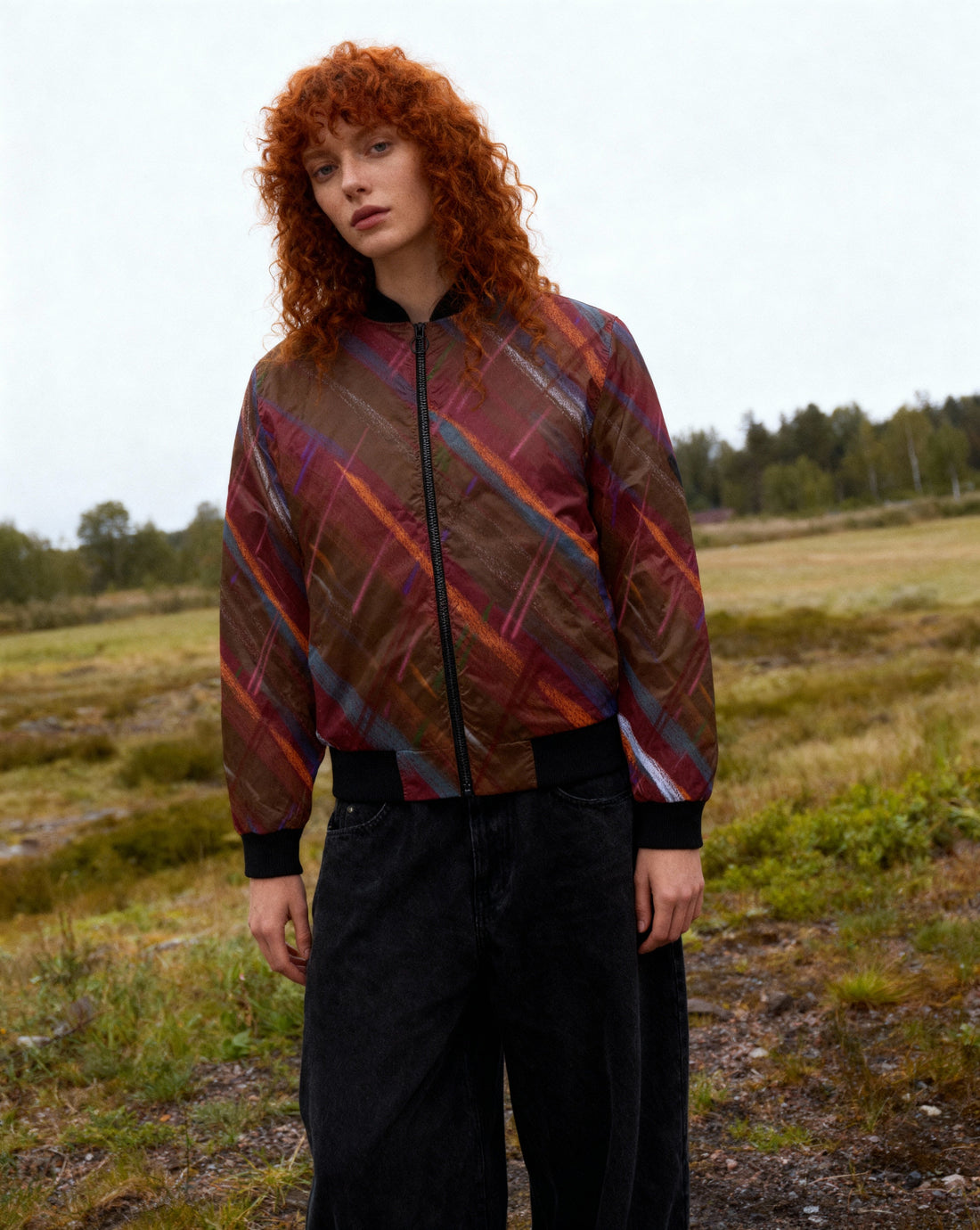 Woman wearing red tartan warm bomber jacket outdoors in autumn setting